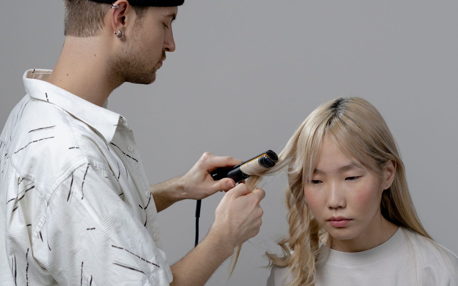 Hairstylist blow-drying a client's hair in a bright salon