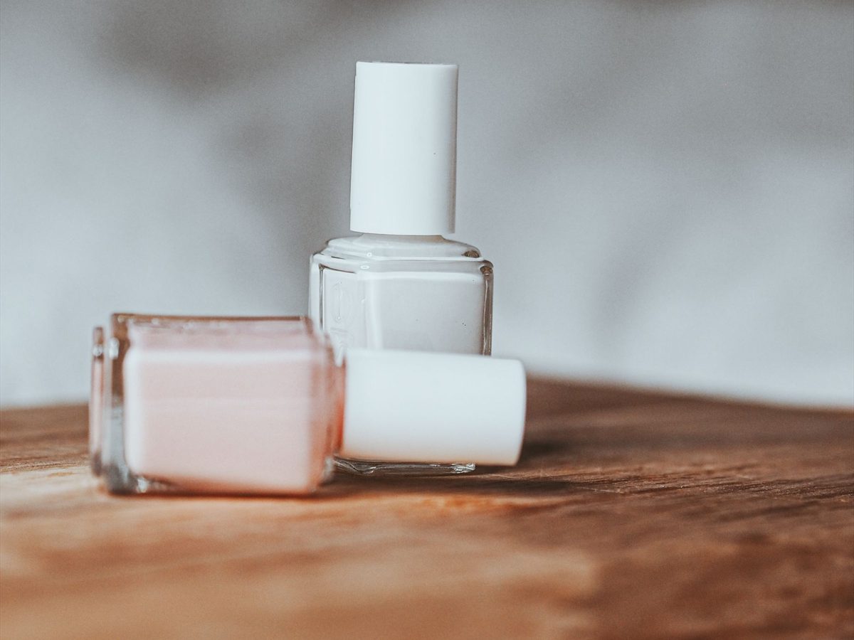 Nail polish bottles and skincare products arranged on a pale surface